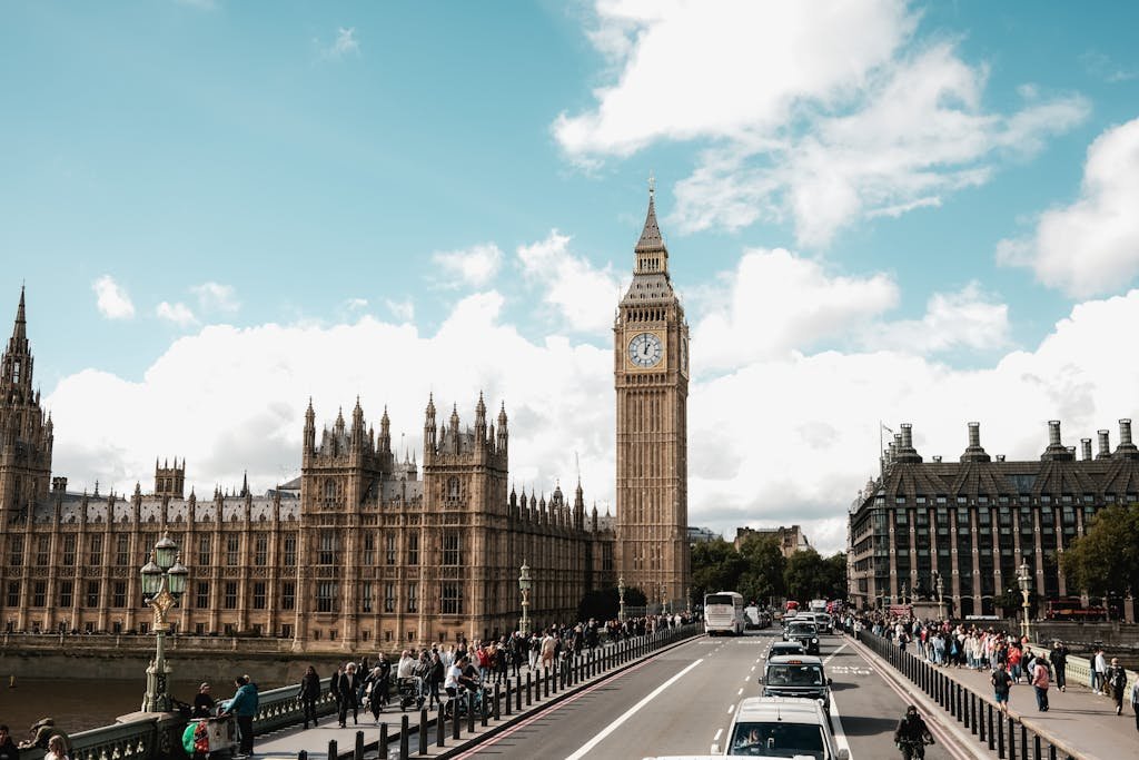 The iconic Big Ben and Westminster Bridge with bustling pedestrians and traffic under a bright sky.